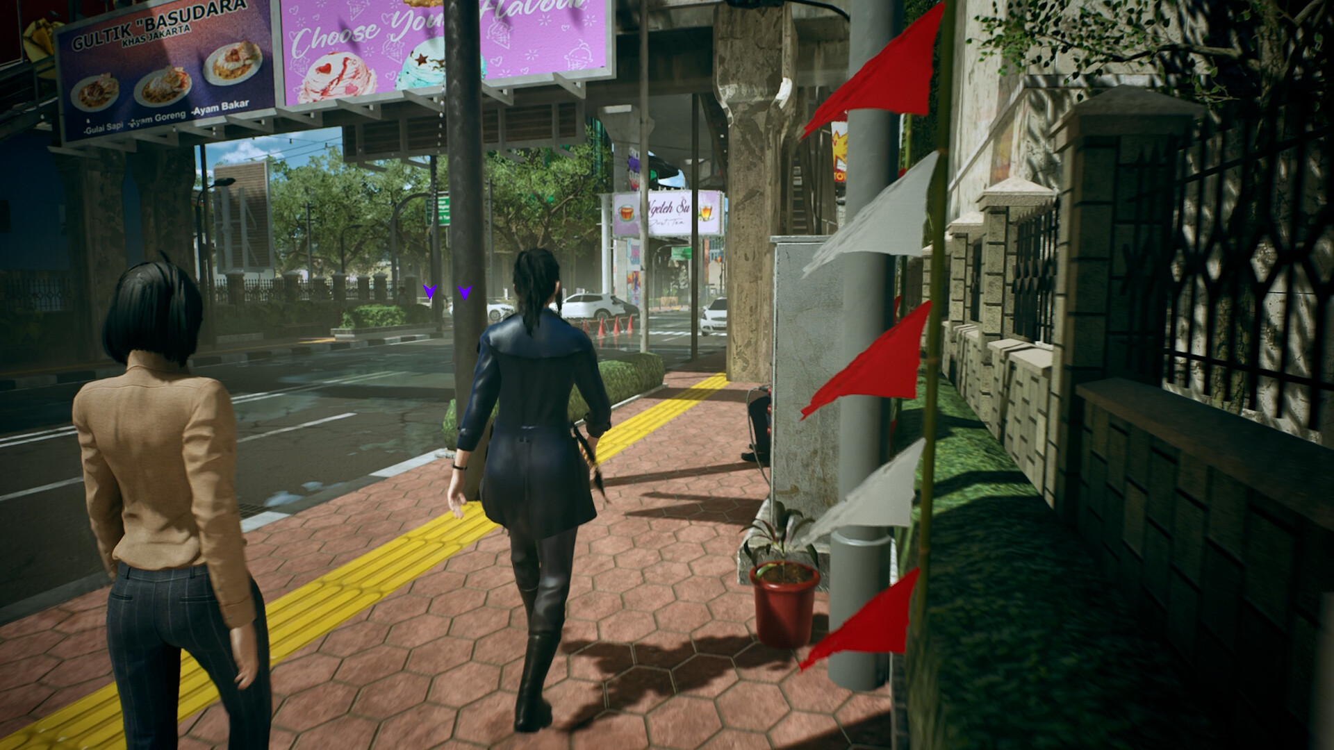 Two women walk along a brick-paved sidewalk under an elevated road, with food billboards overhead and red and white pennants along a fence