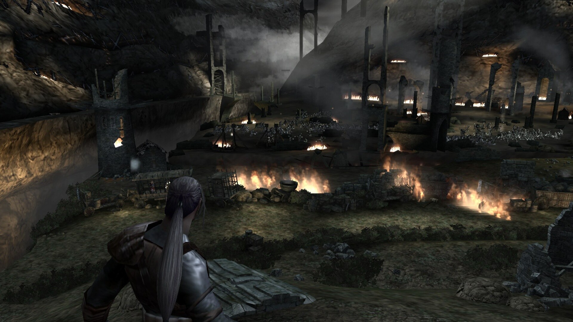 The image depicts a dark, smoky battlefield scene set in a rocky, mountainous area with ruined stone structures scattered throughout. In the foreground, a figure with long gray hair tied back and clad in medieval-style armor is looking out over the scene. The battlefield below is ablaze with multiple fires burning among broken walls and scattered debris, while dense smoke rises into the air, partially obscuring the damaged towers and archways in the distance. Numerous small figures, possibly soldiers, are engaged in combat amid the ruins, contributing to the chaotic and war-torn atmosphere.