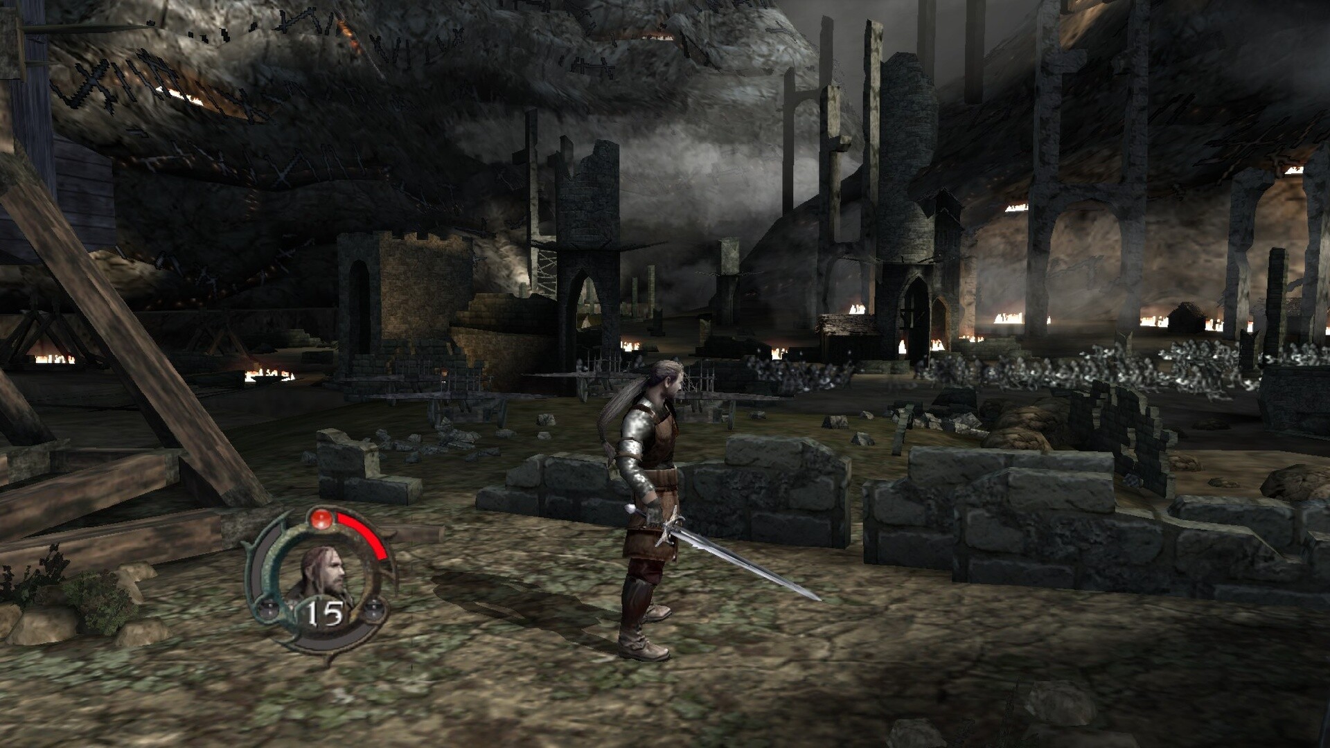 The image depicts a medieval-themed video game scene set in a dark, ruined fortress or battlefield surrounded by stone walls and scattered debris. In the foreground, a character clad in metallic armor and brown leather stands with a long sword held at his side, looking toward the distance. The environment is bleak and dimly lit, with crumbling stone towers and arches, flickering fires, and a misty atmosphere, suggesting an eerie and dangerous location. A circular health or status indicator with the character’s portrait and the number 15 is visible on the bottom left corner of the screen.