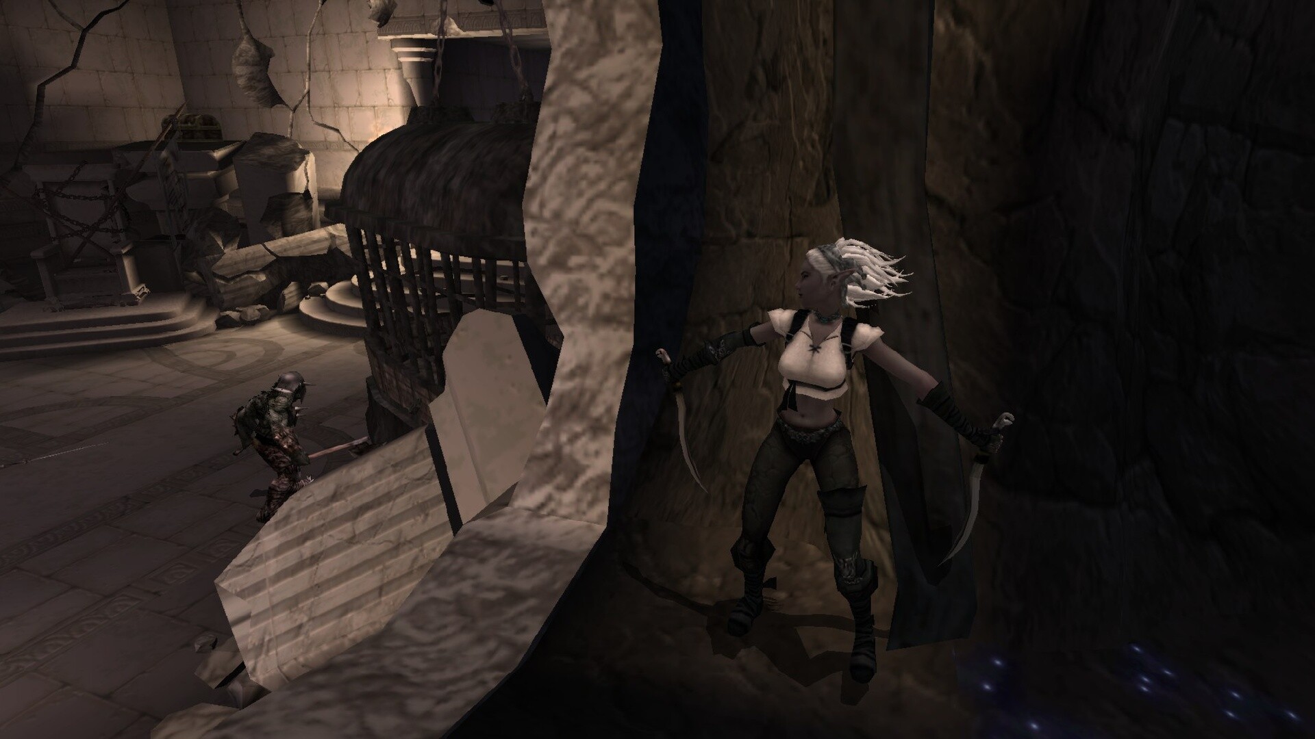 The image depicts a dimly lit, ancient stone chamber with cracked walls and scattered debris. In the foreground, a female character with white hair tied back is crouched behind a large stone pillar, holding two curved daggers and looking cautiously to her left. In the background, another armored figure is standing near a large rusted iron cage, appearing to be unaware of the woman’s presence. The scene conveys a sense of stealth and tension, suggesting a moment of impending confrontation or escape.