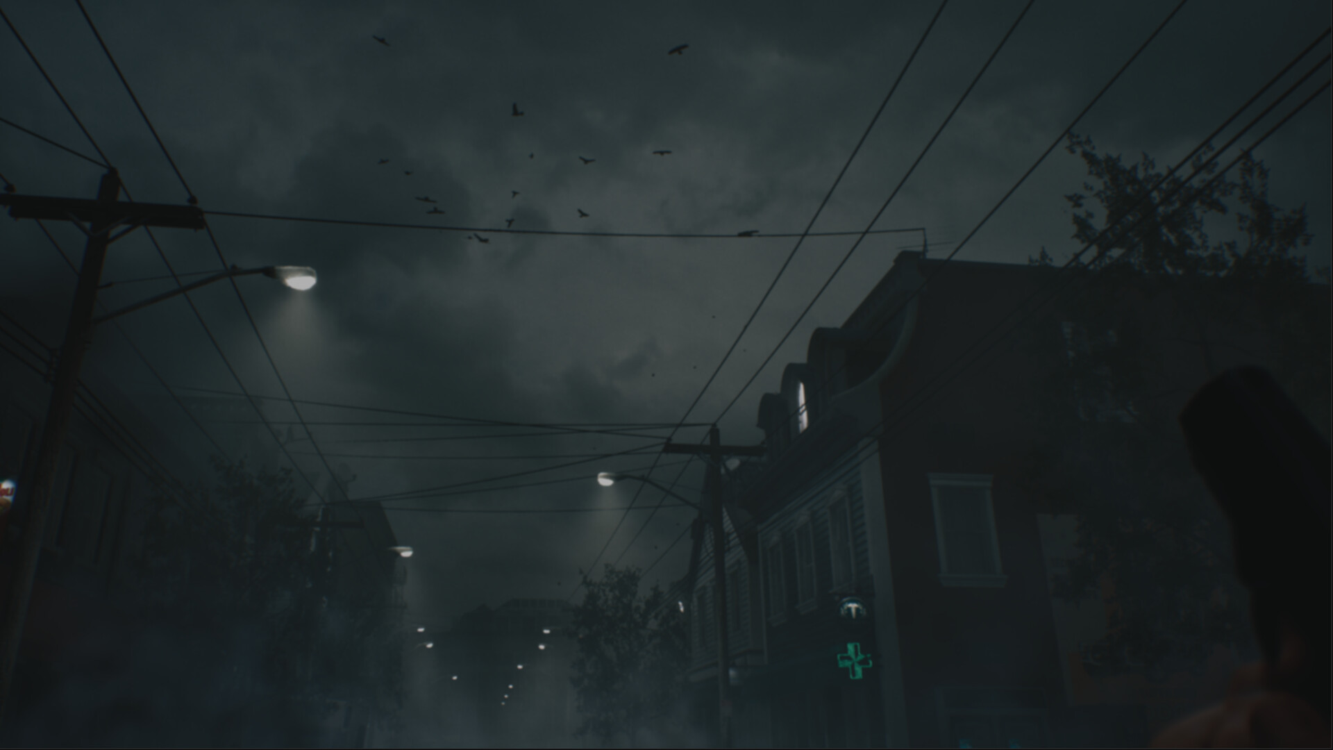 A dark, fog-filled street in Project Night with power lines overhead, glowing streetlights and a green pharmacy cross