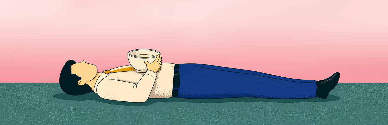 An office worker lies down holding a bowl against a pink background.